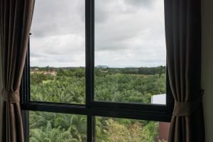 a window with a view of a field of trees at Tha-ruea Residence in Thalang