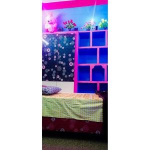Zimmer mit einem Bett und einem Regal mit Pflanzen in der Unterkunft Linga Homestay in Kanchipuram