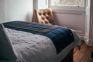 a bedroom with a bed and a chair and a window at The Main Street Burrow - Your Perfect Hideaway in Saint Boswells