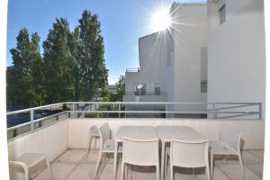 a white table and chairs on the balcony of a building at T2 Résidence Cap Camargue avec piscine in Le Grau-du-Roi