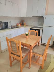 cocina con mesa de madera, 2 sillas y nevera en Apartament 1+1 Plazh Durrës, en Durrës