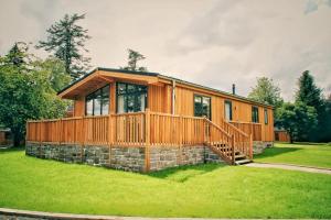 a large wooden house with a stone at Skyline Lodge Loch Lomond Castle Lodges in Balloch