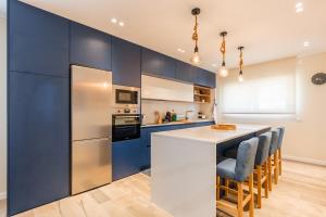 una cucina con armadi blu e bancone con sedie di Vila da Serra 