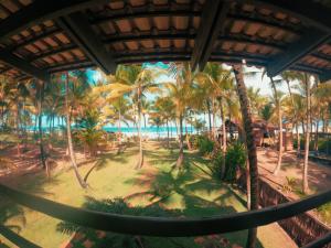 uma vista para a praia a partir de um resort com palmeiras em Bangalô Patuá em Barra Grande