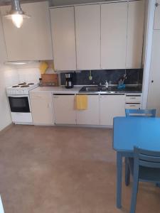 una cocina con armarios blancos y una mesa azul en Willa Witsari 35m2 asunto en Kokkola