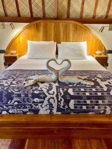 Una cama con dos cisnes hechos para parecer corazones en La Villa Loca, en Gili Air