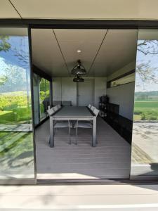 a dining room with a table and large windows at KoppenHerberg in Oudenaarde