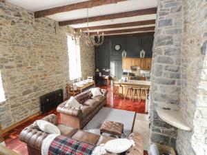 een woonkamer met lederen meubels en een stenen muur bij Millvale Cottage in Cootehill