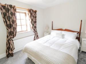 a bedroom with a white bed and a window at Millvale Cottage in Cootehill