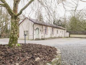 a white building with a tree in front of it at Millvale Cottage in Cootehill