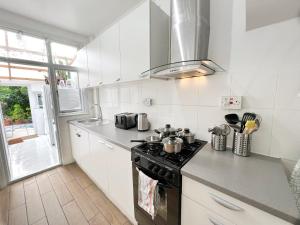 伦敦Luxurious House near Excel- Air Conditioning, 9 Beds, 2 Baths, Garden, fast WiFi的带炉灶的厨房 窗边的顶部烤箱