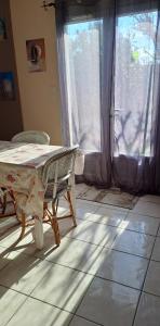 une chambre avec une table, des chaises et une fenêtre dans l'établissement En plein cœur de l’Île d'Oléron, suite parentale., à Dolus-d'Oléron