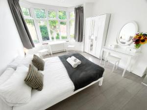 a white bedroom with a large bed and a desk at Luxurious House near Excel- Air Conditioning, 9 Beds, 2 Baths, Garden, fast WiFi in London