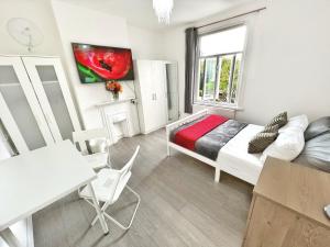 um quarto com uma cama, uma mesa e uma janela em Luxurious House near Excel- Air Conditioning, 9 Beds, 2 Baths, Garden, fast WiFi em Londres