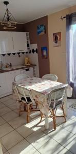 een keuken met een tafel en stoelen in een kamer bij En plein cœur de l’Île d'Oléron, suite parentale. in Dolus d'Oléron