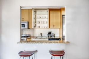 eine Küche mit Holzschränken und drei Hockern in der Unterkunft Corner 1BR in W Village w Doorman NYC-157 in New York + 14 Fotos