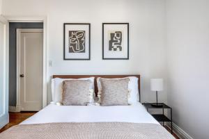 ein Schlafzimmer mit einem weißen Bett mit drei Bildern an der Wand in der Unterkunft Corner 1BR in W Village w Doorman NYC-157 in New York