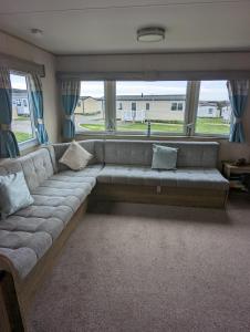 a couch in a living room with a large window at Haven Holiday Home Littlesea Sleeps 6 in Weymouth