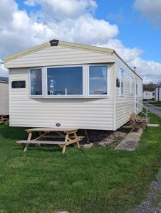 a white tiny house with a picnic table in the grass at Haven Holiday Home Littlesea Sleeps 6 in Weymouth