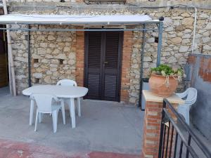 uma mesa branca e cadeiras em frente a um edifício em CASA VACANZE Monte Venere em Castelmola