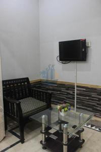 een kamer met een stoel, een tafel en een tv bij Sk Travellers Inn in Karachi