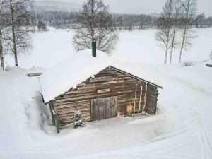 a small wooden cabin with snow on top of it at Yurt District in Rovaniemi