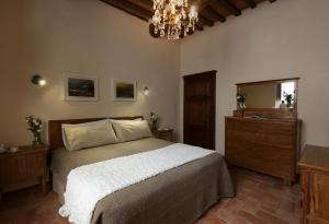 Schlafzimmer mit einem Bett, einem Spiegel und einem Kronleuchter in der Unterkunft PienzaLettings "Casa Olivieri" in Pienza
