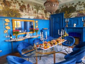 una sala da pranzo blu con tavolo in vetro e sedie blu di Chateau Tanesse de Tourny a Bayon