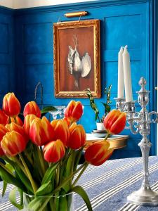 un vase de tulipes rouges dans une pièce bleue avec un tableau dans l'établissement Chateau Tanesse de Tourny, à Bayon