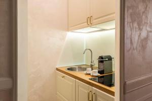 eine kleine Küche mit einem Waschbecken und einem Spiegel in der Unterkunft Frattina Elegance Suite in Rom