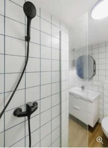 ein weiß gefliestes Bad mit einer Dusche und einem Waschbecken in der Unterkunft Stay in Kaunas & LA51 - Free Parking in Kaunas