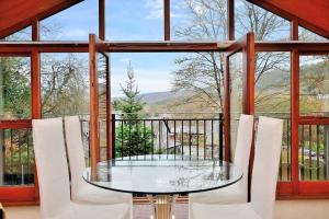 a glass table and chairs in a room with a window at Betws Y Coed Serviced Holiday Home in Betws-y-coed