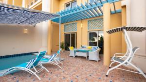 um pátio com cadeiras, uma mesa e uma piscina em Exclusive Retreat GLOBALSTAY's New 3BR Townhouse with Private Pool em Dubai