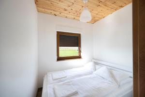 a bedroom with a white bed and a window at Kwiat Paproci in Gąski