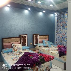 2 Betten in einem Zimmer mit blauen Wänden in der Unterkunft ستانلي اسكندريه in Alexandria