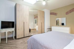 Schlafzimmer mit einem Bett, einem TV und einem Spiegel in der Unterkunft House Under the Tower by Studio Vita in Bologna