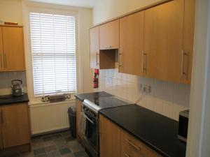 a kitchen with wooden cabinets and a black counter top at Lovely Spacious 3 Bedded First Floor Apartment in Ryde