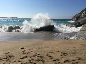 a wave crashing on a beach with footprints in the sand at Dog Friendly Stylish Modern Flat, near Beach in Newquay