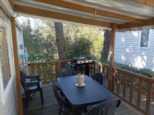 a table and chairs on a deck with a grill at Beau Mobil home 64 in Saint-Jean-de-Monts