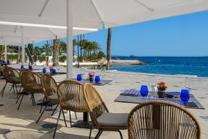uma mesa com cadeiras e um guarda-sol na praia em Hotel Vibra Marítimo em Cidade de Ibiza
