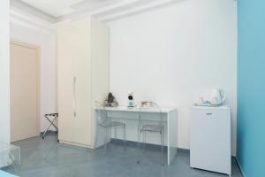 Camera bianca con tavolo, sedie e frigorifero. di Guest House Emily Suites Sorrento a Sorrento