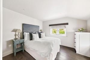 a white bedroom with a bed and a window at Chantry House in Barnsley