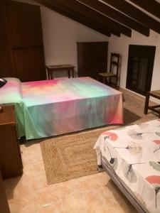 a bedroom with a bed with a rainbow bedspread at Finca La Pimienta in Pizarra