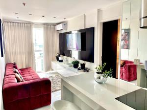 a living room with a red couch and a tv at Metropolitan Flamboyant in Goiânia