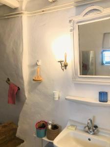 a white bathroom with a sink and a mirror at Thimari cottage in Andros in Agios Petros