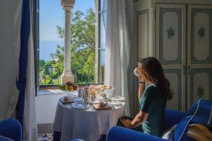 a woman sitting at a table near a window at Hotel Villa Cimbrone in Ravello