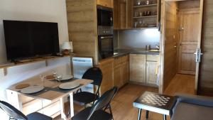 a kitchen with a table and chairs and a television at Woody Studio Les Menuires in Levassaix