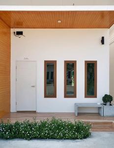 a white house with a white door and windows at Hey Sunday Home in Ban Mit Mongkhon