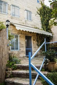 ein Haus mit einem blauen Geländer vor einem Gebäude in der Unterkunft Peled House of Art in Mevasseret Zion