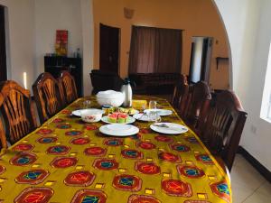 a dining room table with a yellow table cloth with food on it at Pazuri House Iringa in Iringa